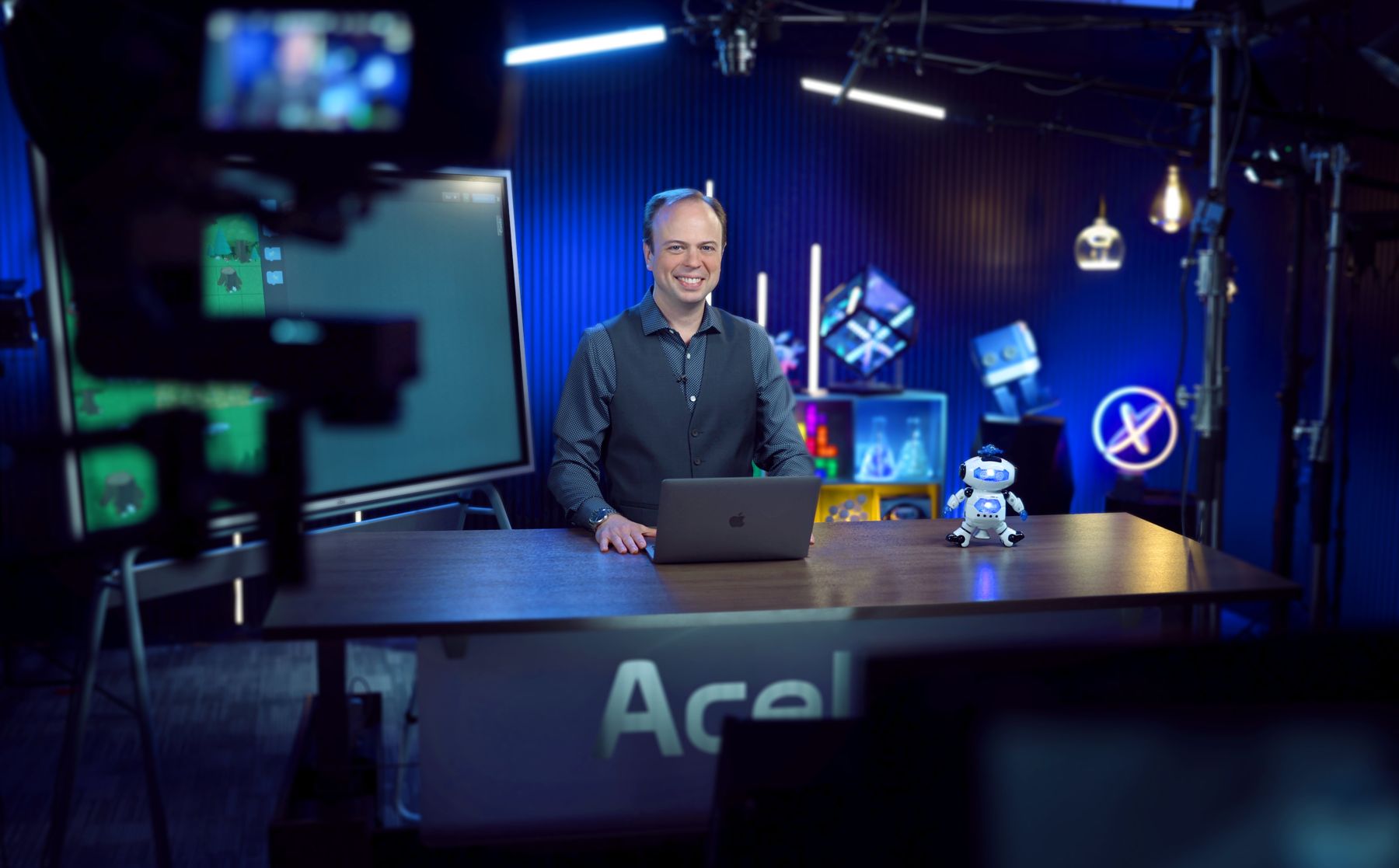 Dr. John at the desk on an Acellus Film Studios set, with a camera in the foreground