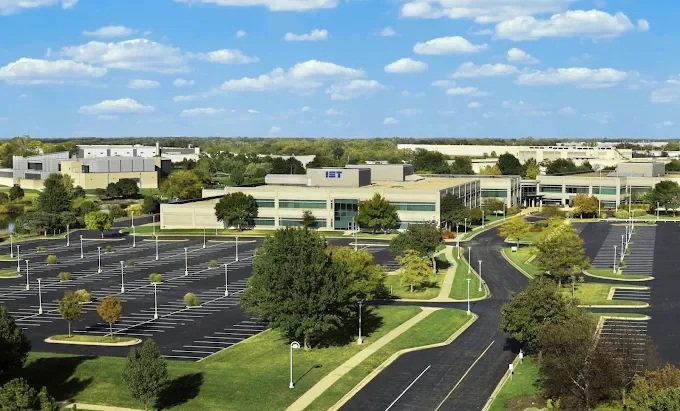 Aerial view of the Institute of Science and Technology campus in Kansas City, Missouri: a long white building with the IST sign, surrounded by trees and parking lots